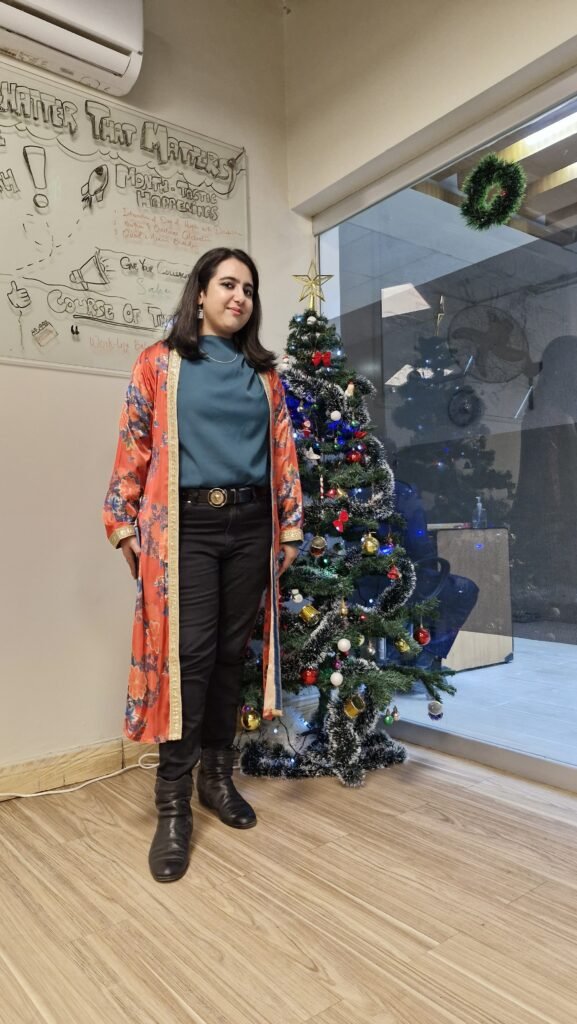 SaharButtSEO Picture of Sahar Butt SEO Specialist standing beside a Christmas tree in her office.